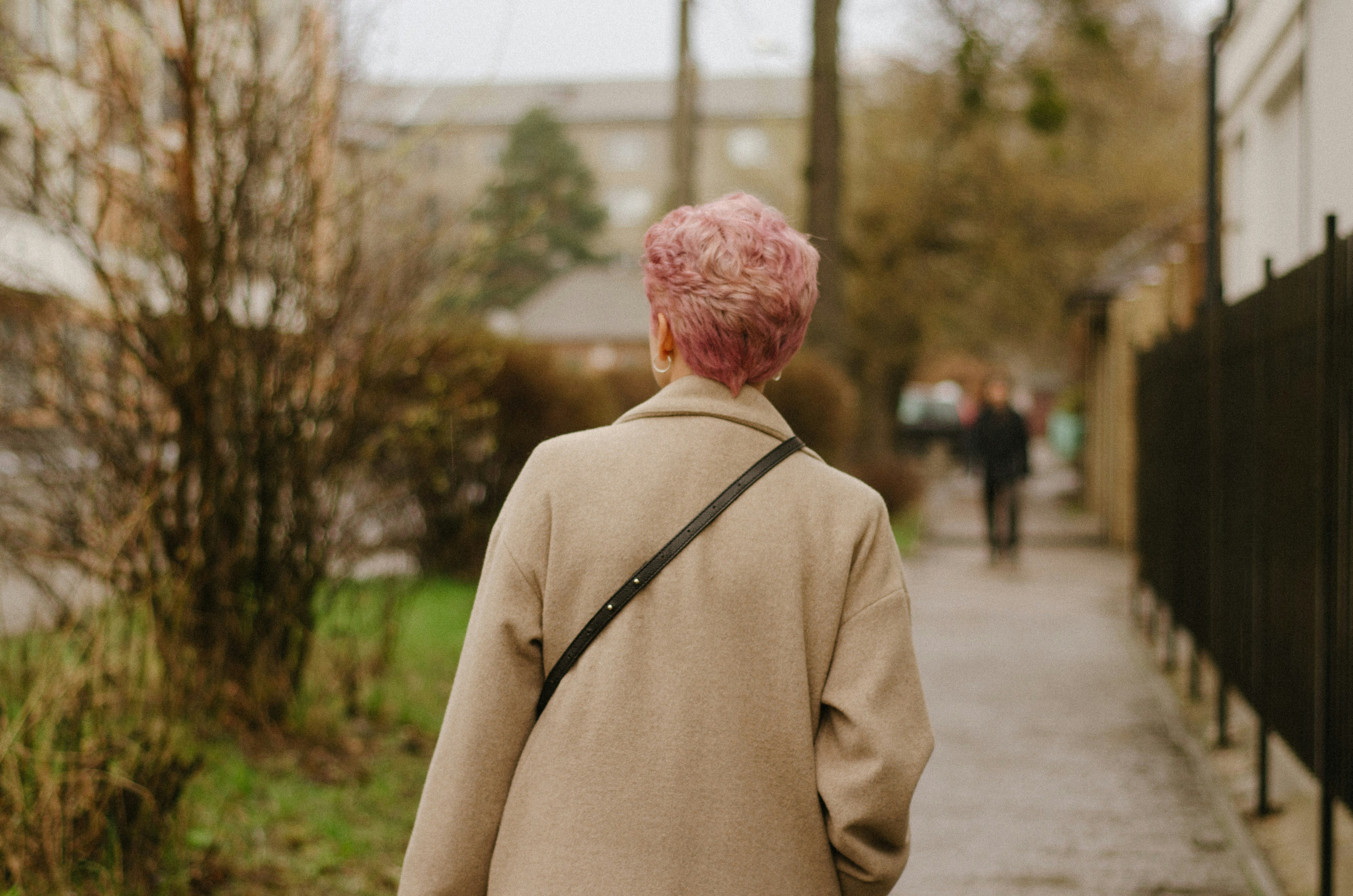 Una mujer con cabello rosado caminando por una acera