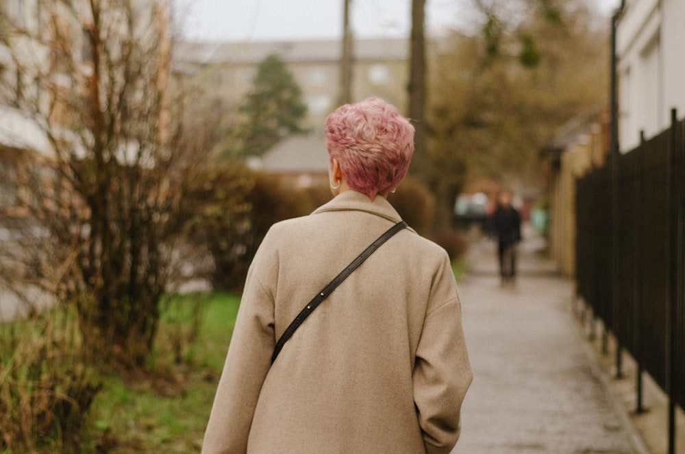 a woman with pink hair walking down a sidewalk