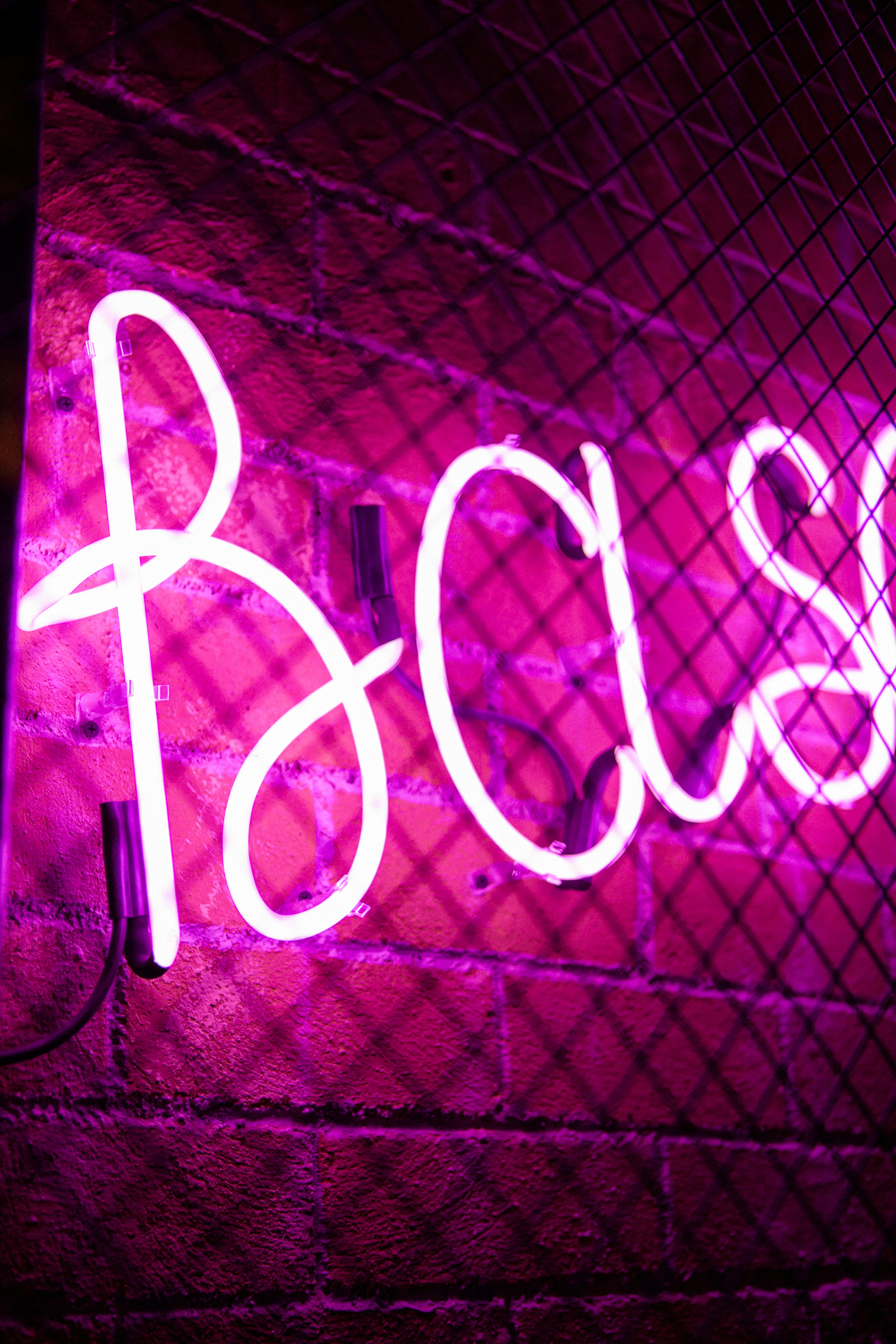 a neon sign that reads boss on a brick wall