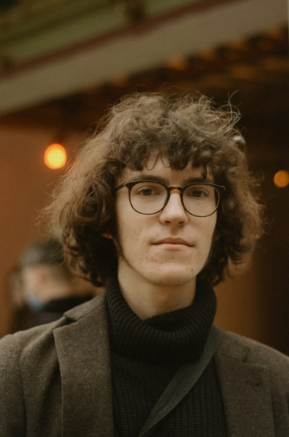 a man wearing glasses and a black turtle neck sweater