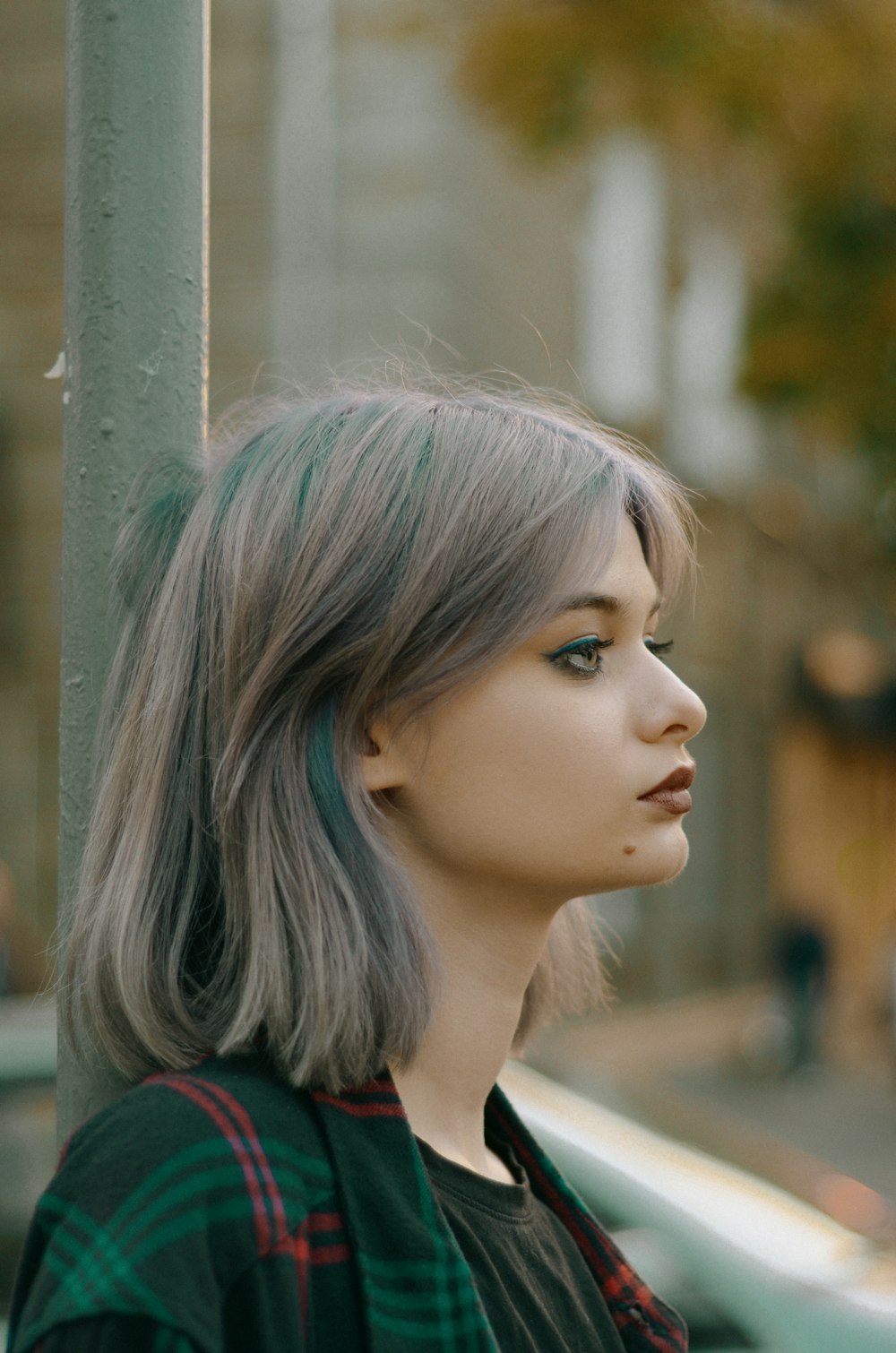 a woman with grey hair standing next to a pole