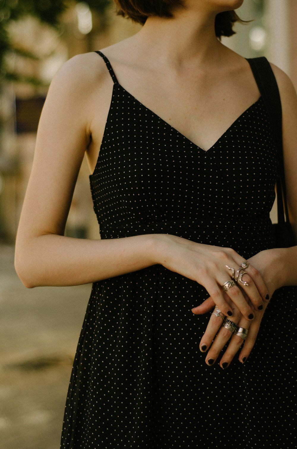 a woman in a black dress holding her hands together