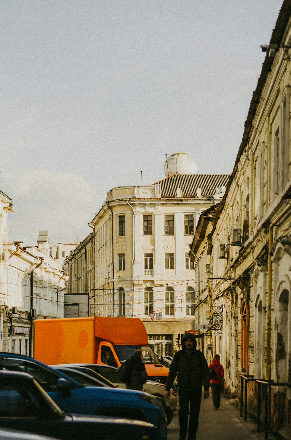 a man walking down a street next to tall buildings