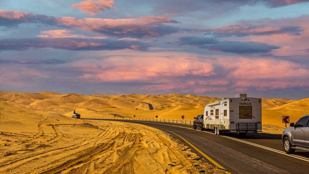 a truck driving down a desert road next to a trailer