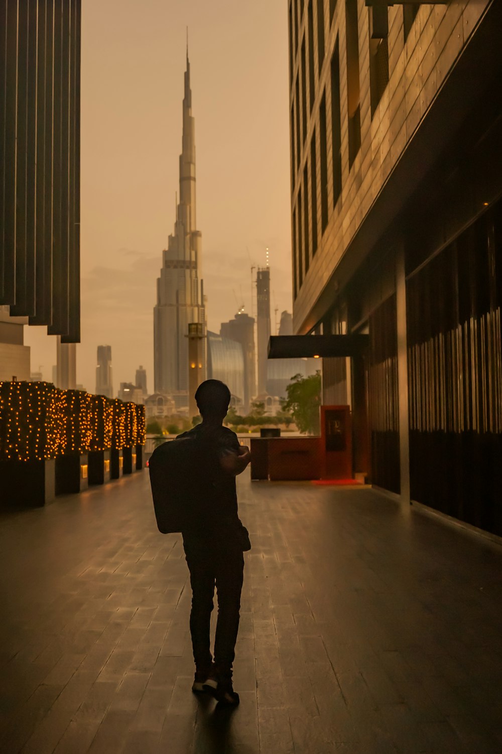 a man walking down a sidewalk in front of a tall building