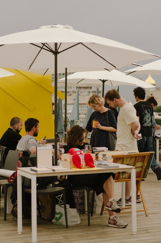 a group of people sitting at a table under umbrellas