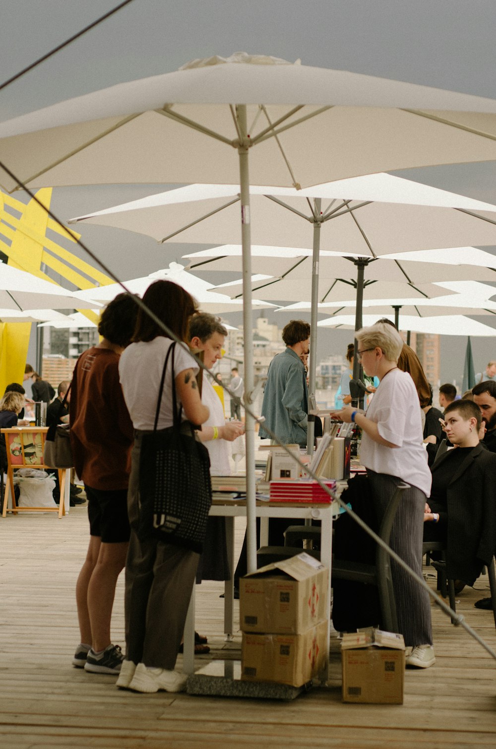 a group of people standing around a table under an umbrella