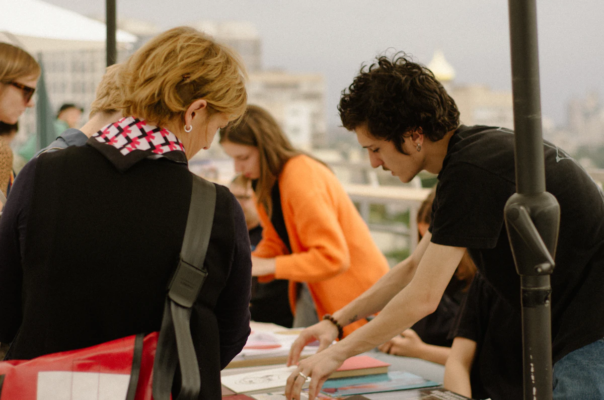 Four colleagues standing over a table of printed pages by a window, reading through them together