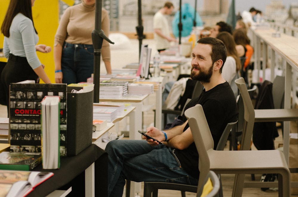 a man sitting in a chair next to a table full of books