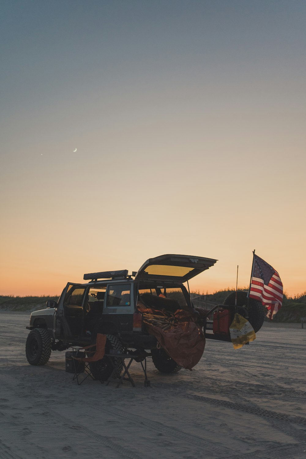 Ein am Strand geparkter Jeep mit amerikanischer Flagge