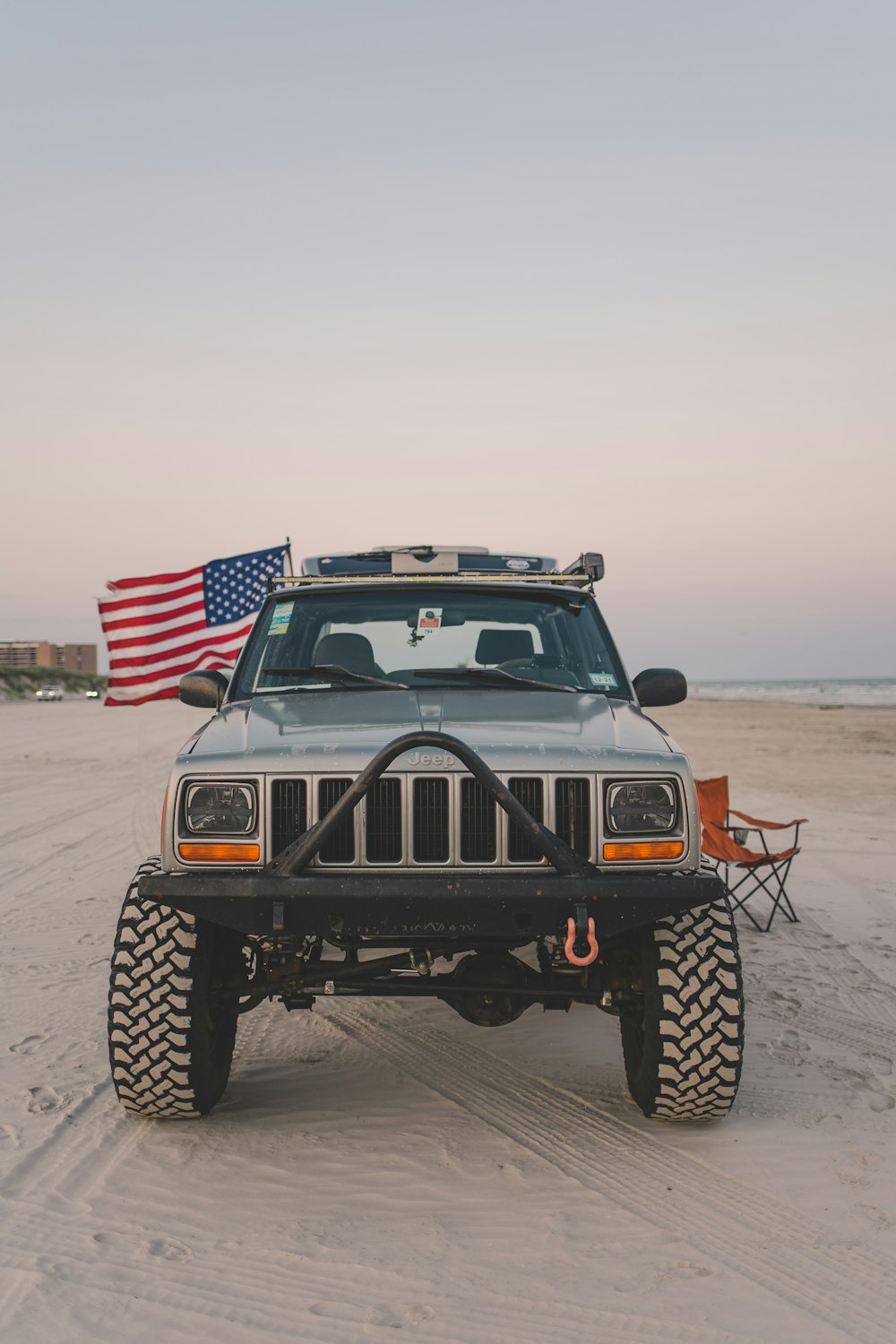 a truck parked on the beach with an american flag in the background