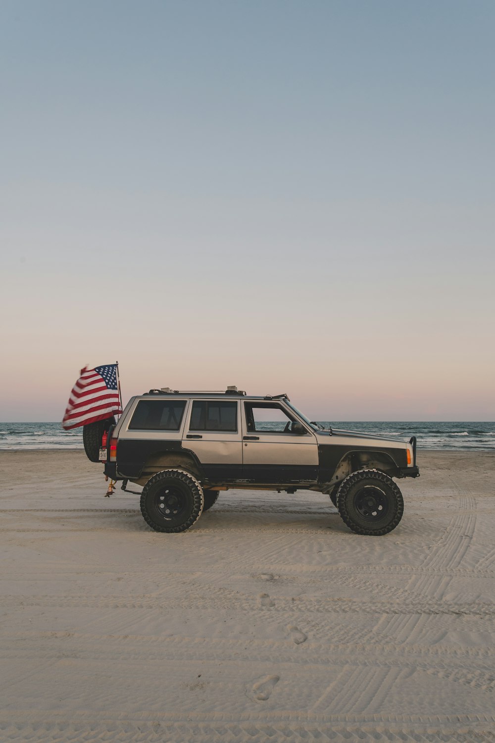 a jeep with an american flag on the beach