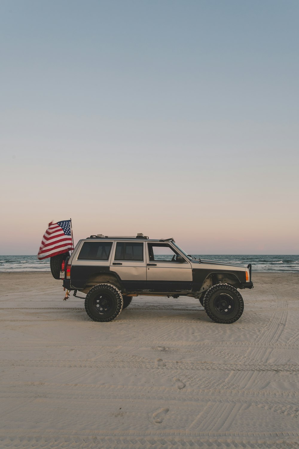 Ein Jeep mit amerikanischer Flagge am Strand