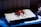 A folder with a distinctive graphic artwork featuring a red figure on a skateboard against a cream background. The folder rests atop a blue surface, with other materials partially visible underneath. The scene is contrasted by shadows.