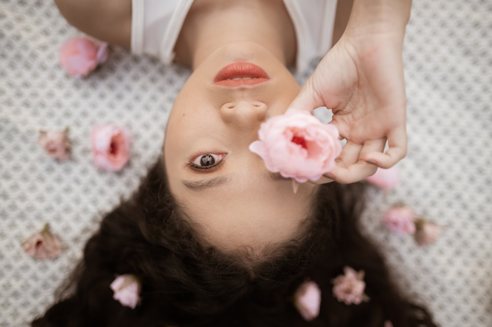 a woman laying on the ground with a flower in her hand