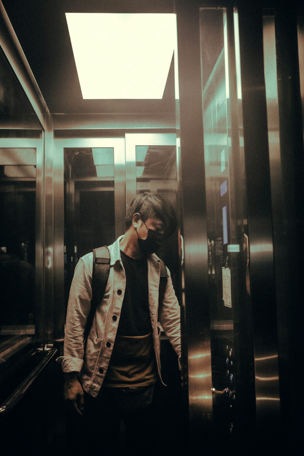 a man wearing a face mask standing in an elevator