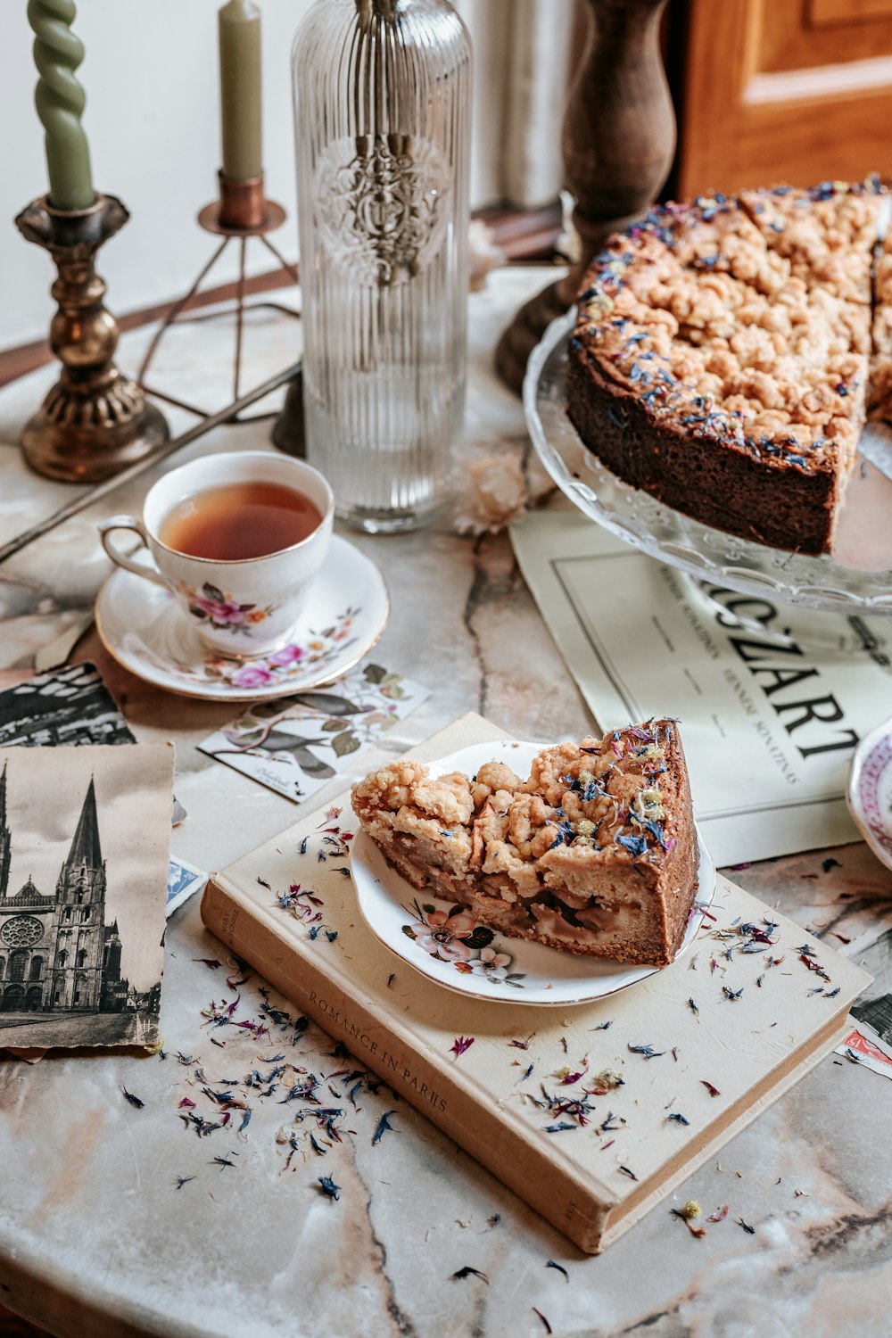 una mesa cubierta con una rebanada de pastel junto a una taza de té