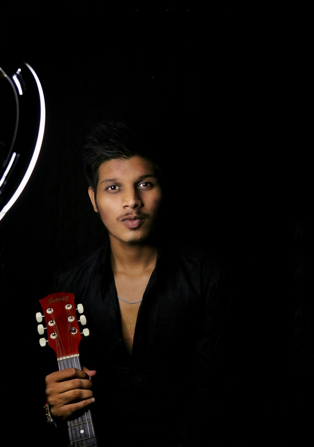 a man holding a red guitar in front of a black background