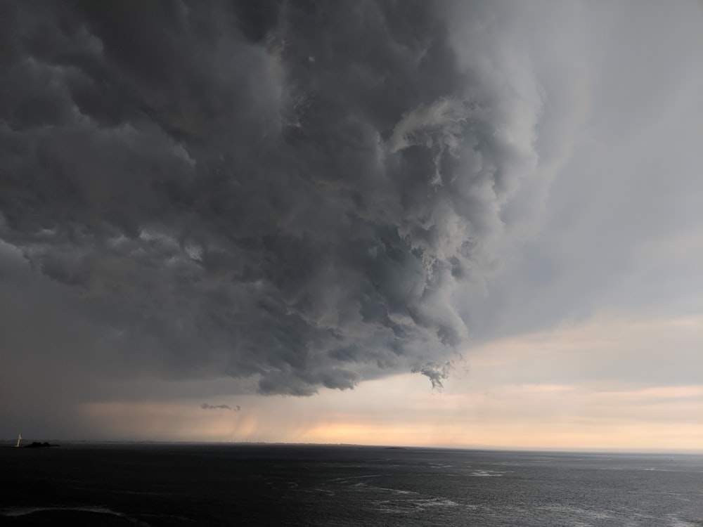 a large storm cloud looms over a large body of water