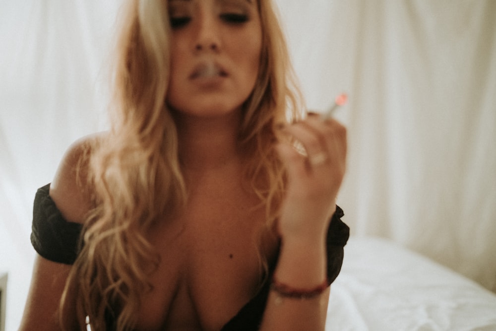 a woman smoking a cigarette on a bed