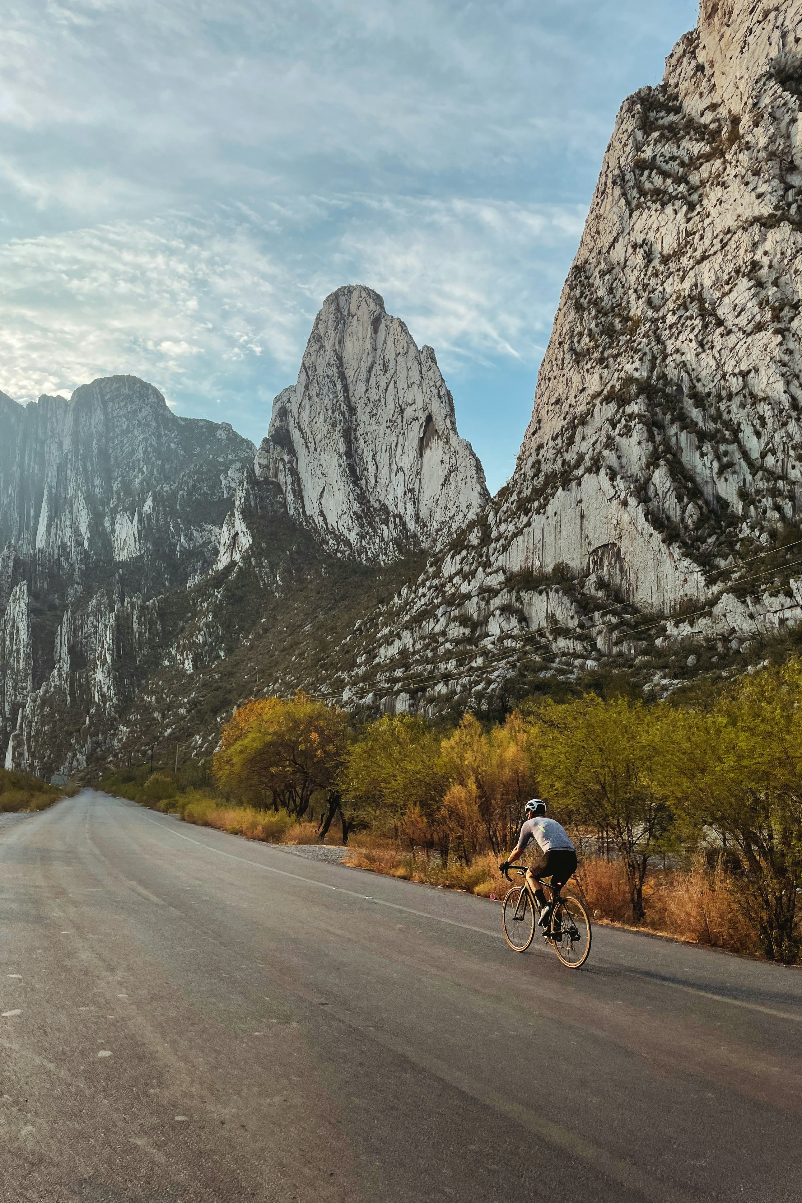 a man riding a bike down a road next to mountains