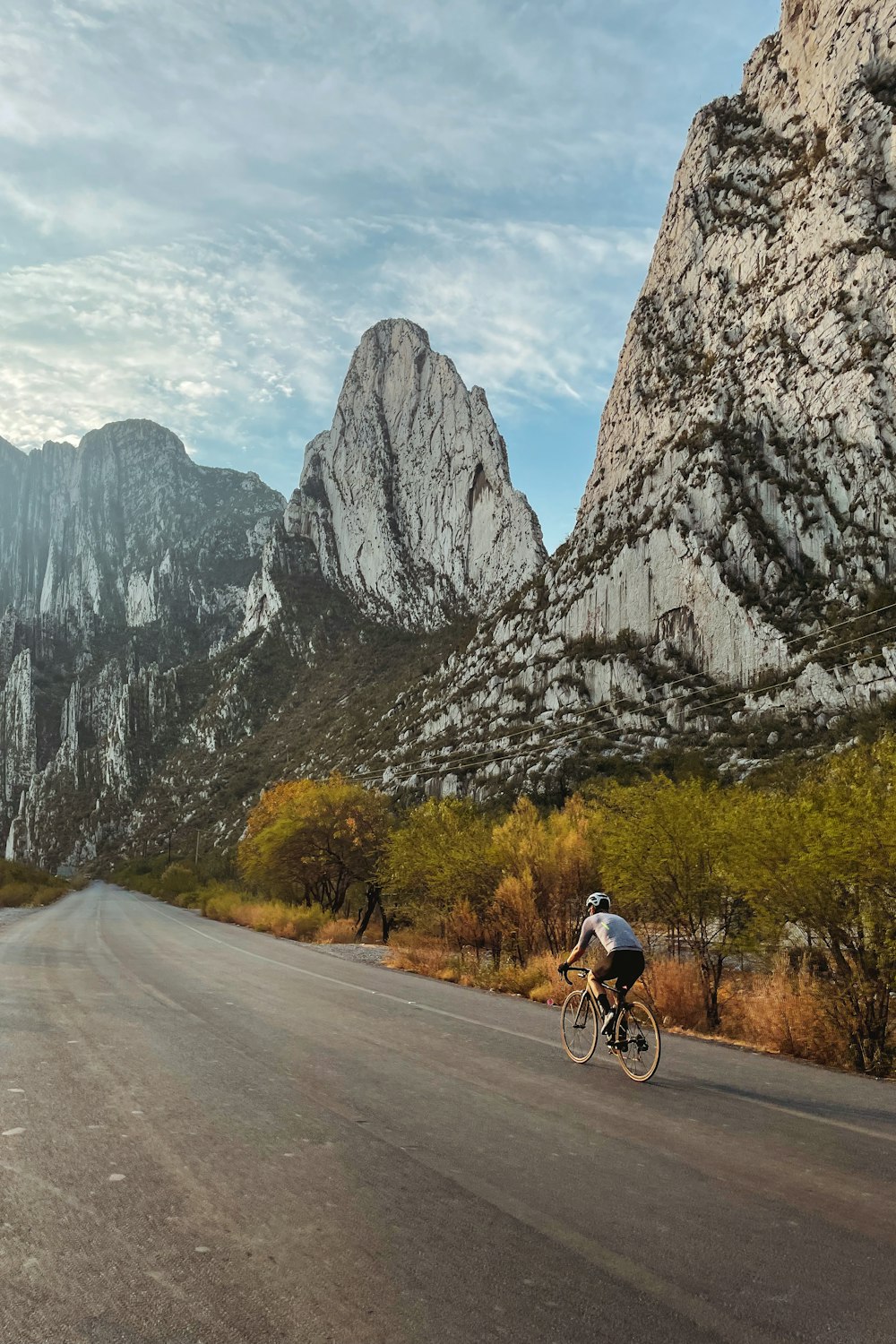 a man riding a bike down a road next to mountains