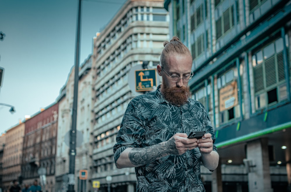 a man with a beard is looking at his cell phone