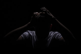 a man in the dark covering his face with his hands