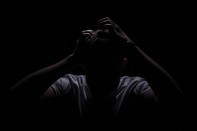 a man in the dark covering his face with his hands