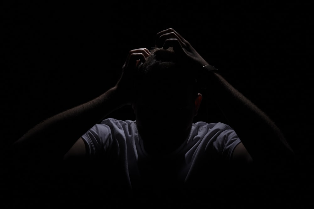 a man in the dark covering his face with his hands