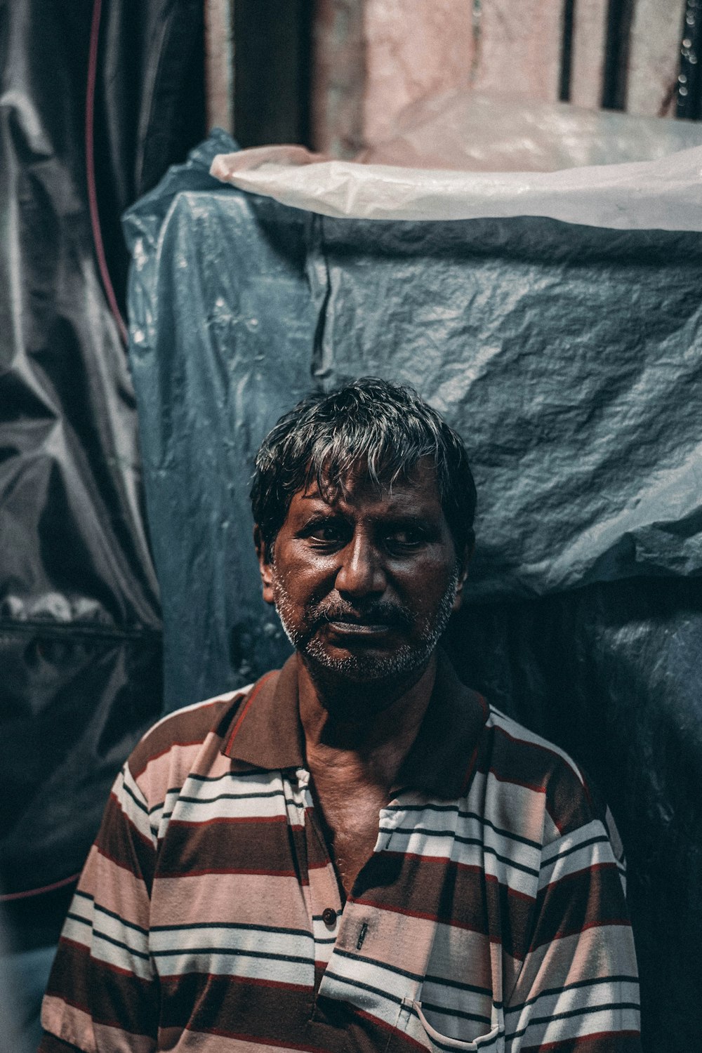 a man in striped shirt sitting in front of a black tarp