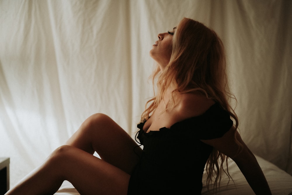 a woman sitting on a bed with her legs crossed