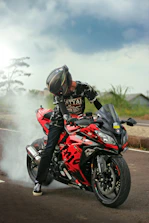 a man riding a red motorcycle down a street