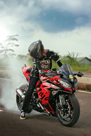 a man riding a red motorcycle down a street