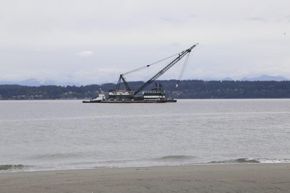 a large crane is on the water near a beach