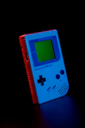 Stacks of retro Gameboy cartridges and handheld consoles glowing under soft lighting.