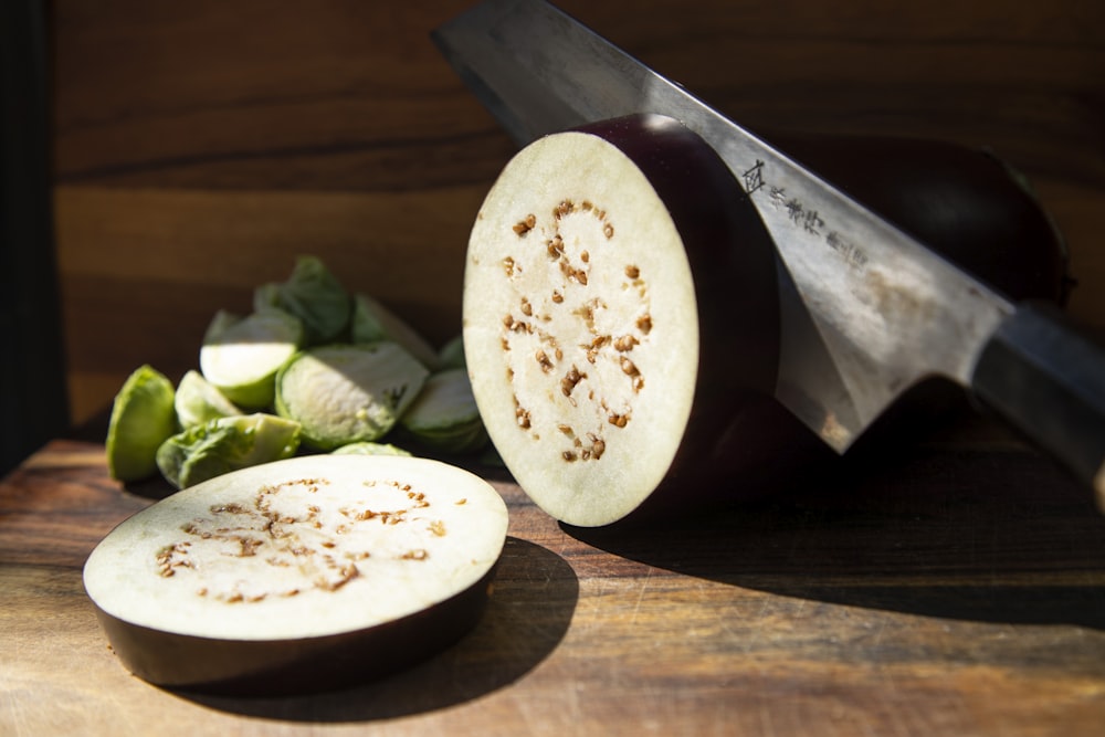 a sliced up eggplant next to a knife on a cutting board