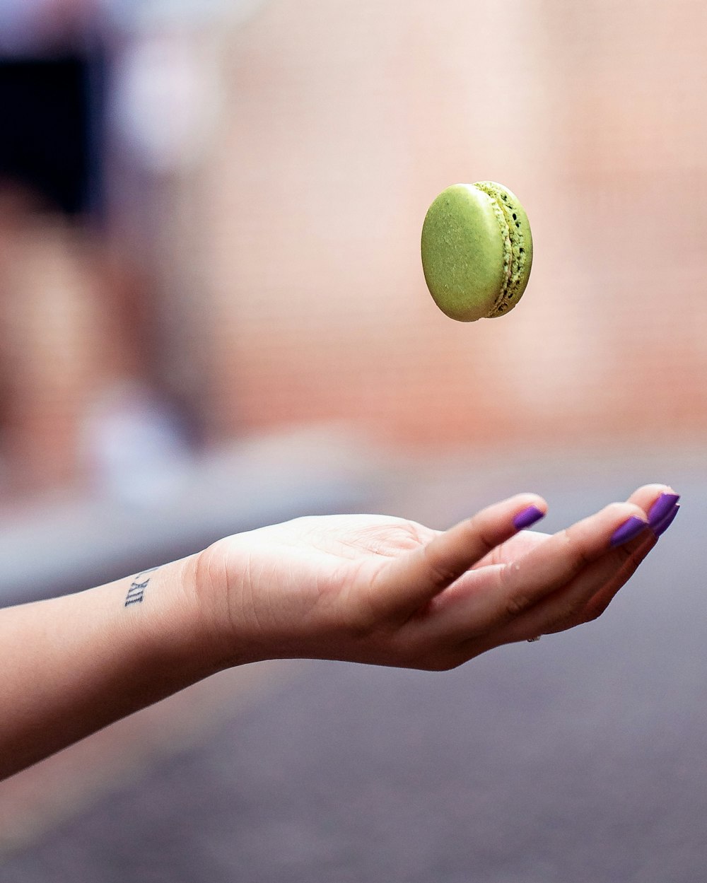 a woman's hand holding a green doughnut in the air