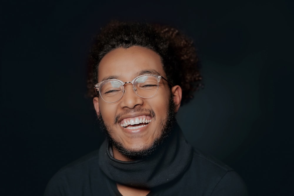 a man with glasses and a scarf smiling