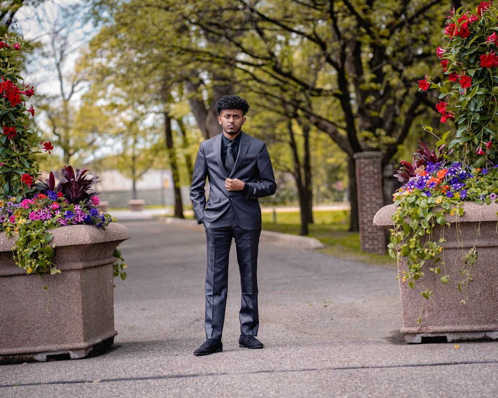 a man in a suit standing in front of some flowers