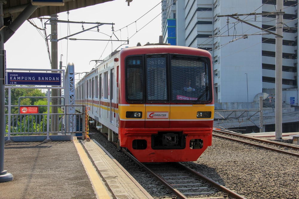 Un tren rojo y amarillo entrando en una estación de tren