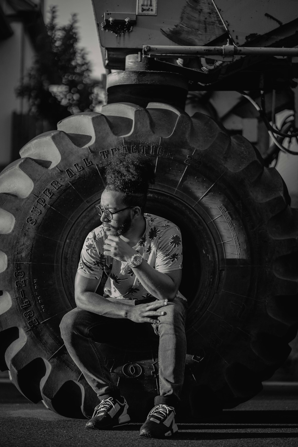 a man sitting in front of a giant tire