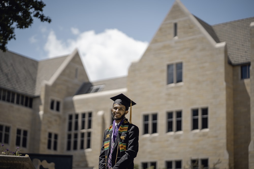 a man in a graduation gown standing in front of a building