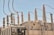 An array of electrical insulators and conductors on top of a large power transformer. The insulators have a cylindrical, ribbed design to prevent electrical leaks, and there are several wires and cables connected to them. Cooling fans are visible on the side of the transformer.