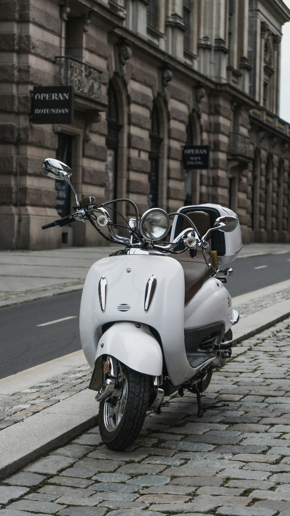 a white scooter parked on the side of a street