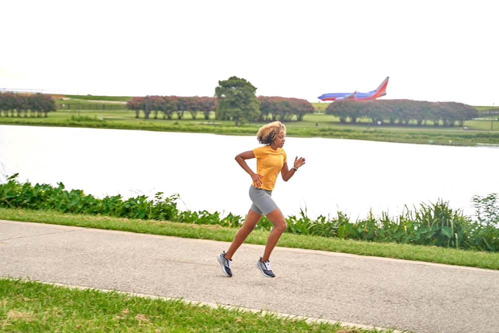 a woman running down a path next to a lake