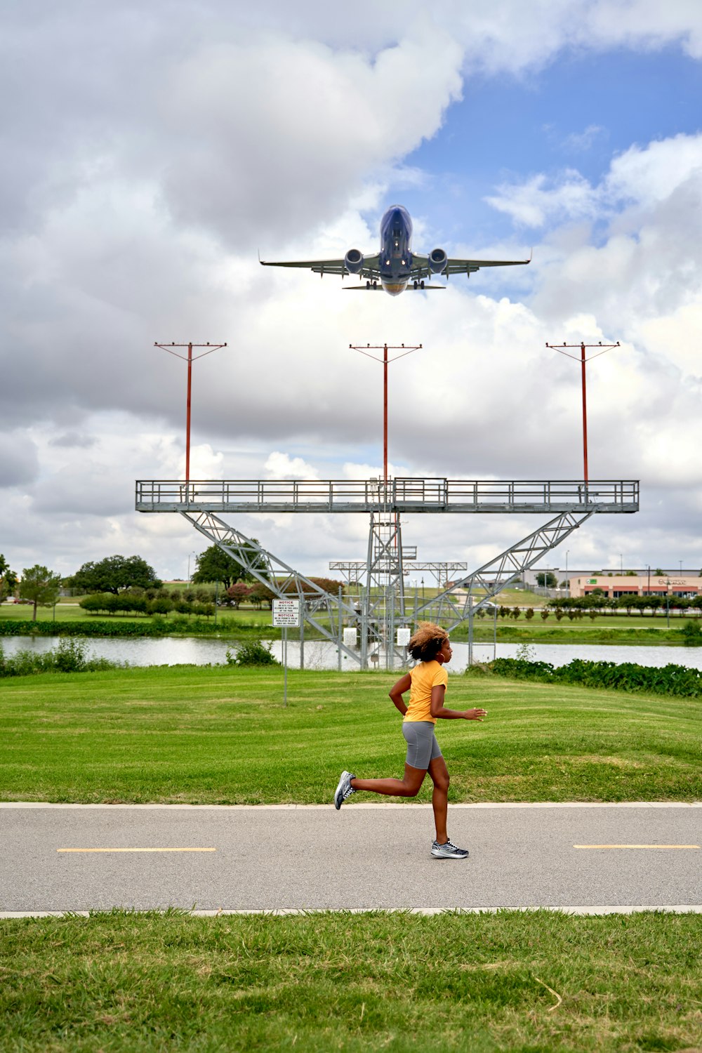 a woman running down a road in front of an airplane