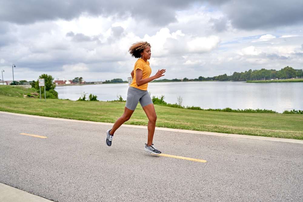 a woman running down a street next to a lake