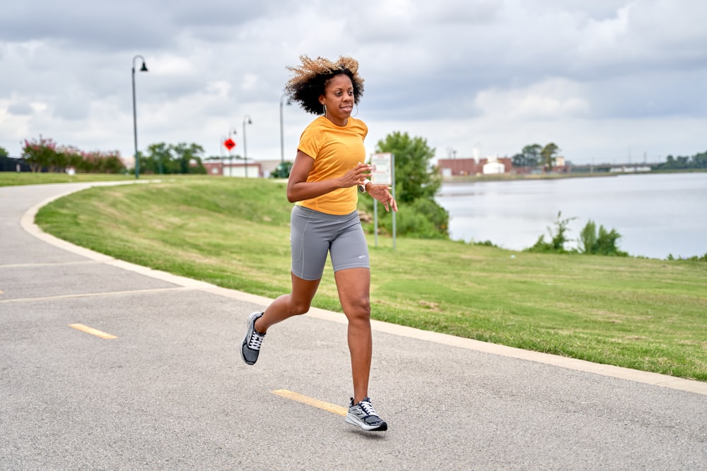 a woman running down a road next to a lake