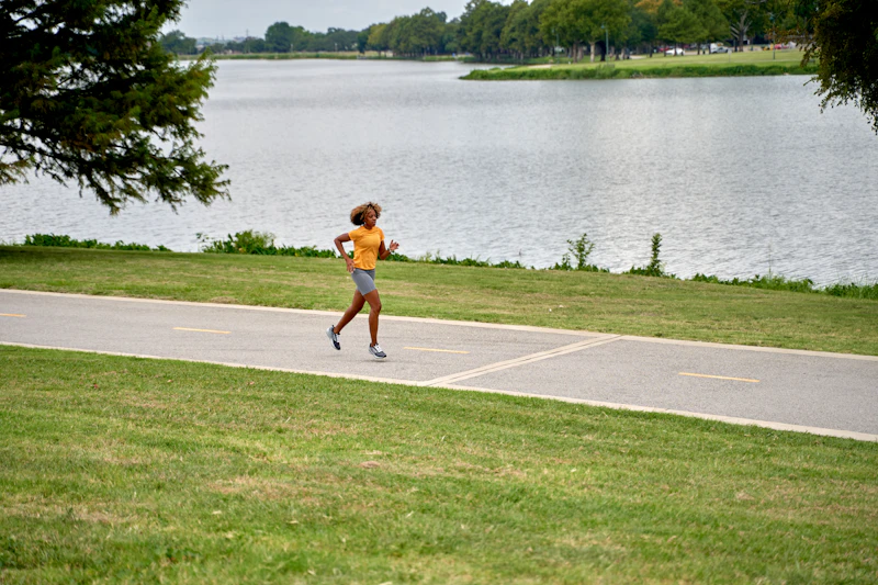 A runner on a lakeside trail lined with green trees